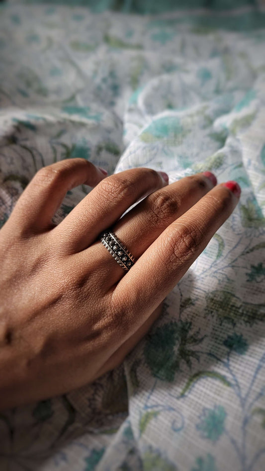 Hand with Aadi ring on a patterned fabric background