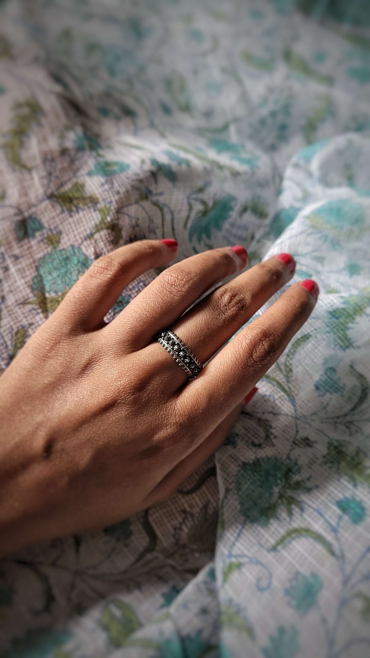 Hand with a ring on a patterned fabric background