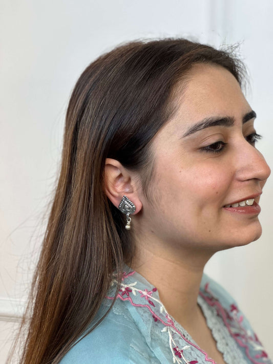 Woman wearing a diamond silver earring with a light background