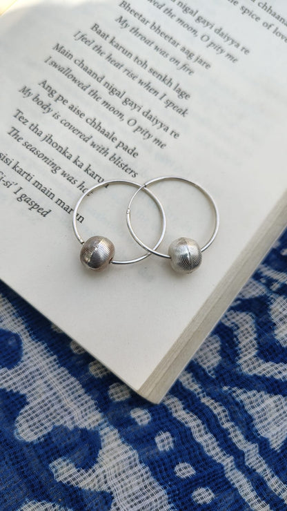 Silver hoop earrings with beads on an open book