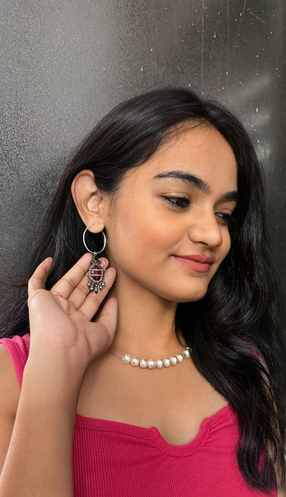 Woman wearing earrings and a necklace, posing against a dark background