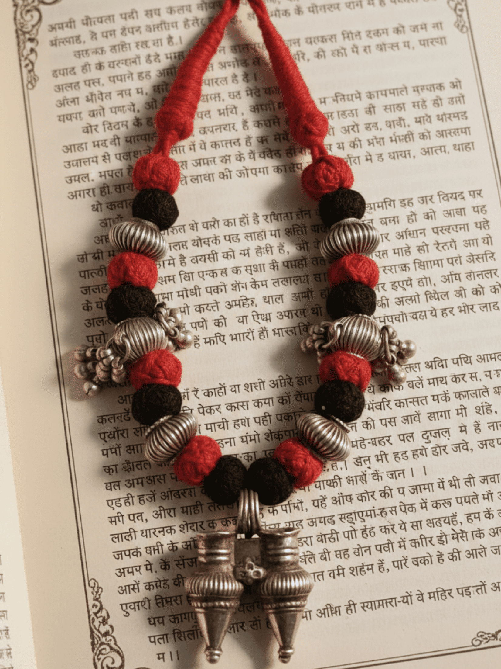 Necklace with red, black, and silver beads on a printed text background