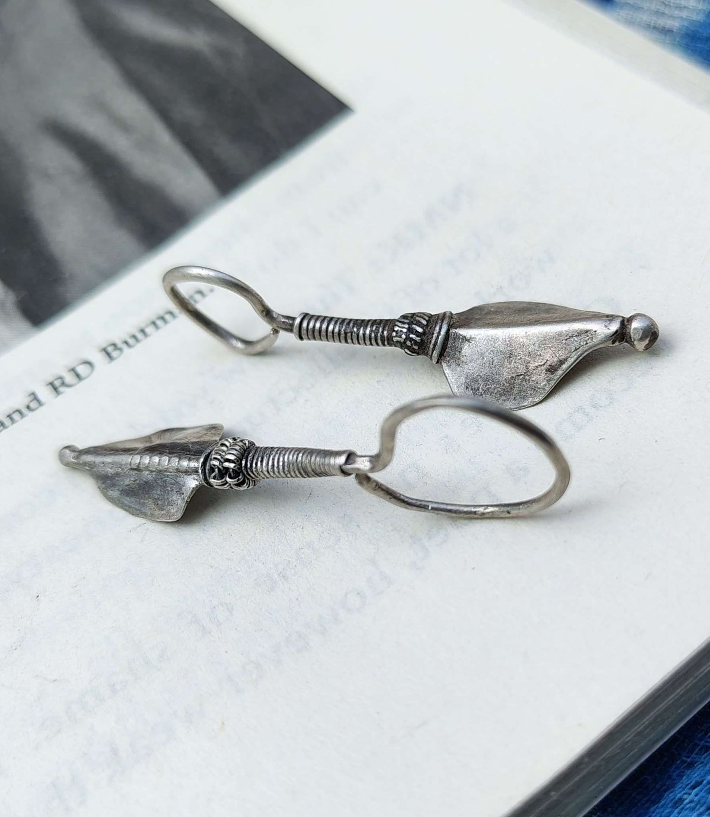 Pair of silver earrings on an open book with a blurred background