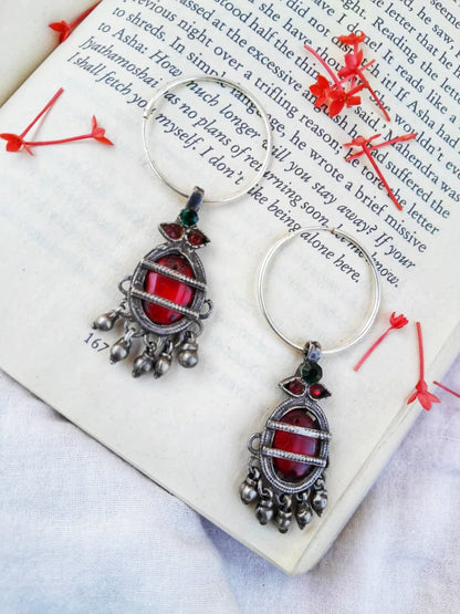 Pair of silver earrings with red gemstones on a book page