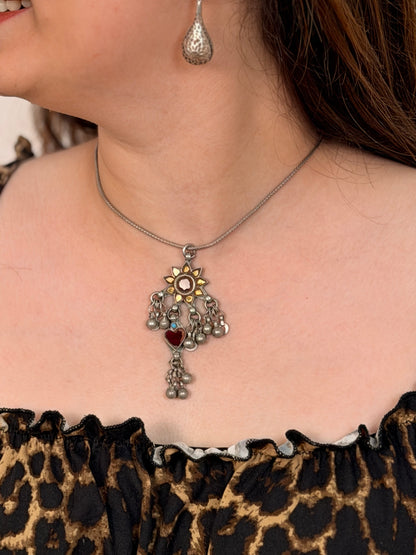 A rare vintage silver maximalist pendant — hand-cut glass sunflower with red centre and yellow petals, maroon glass heart dangler, turquoise accent, dense ghungroos and geometric danglers throughout. Available with or without chain. Shop Sadabahaar Jewelry.