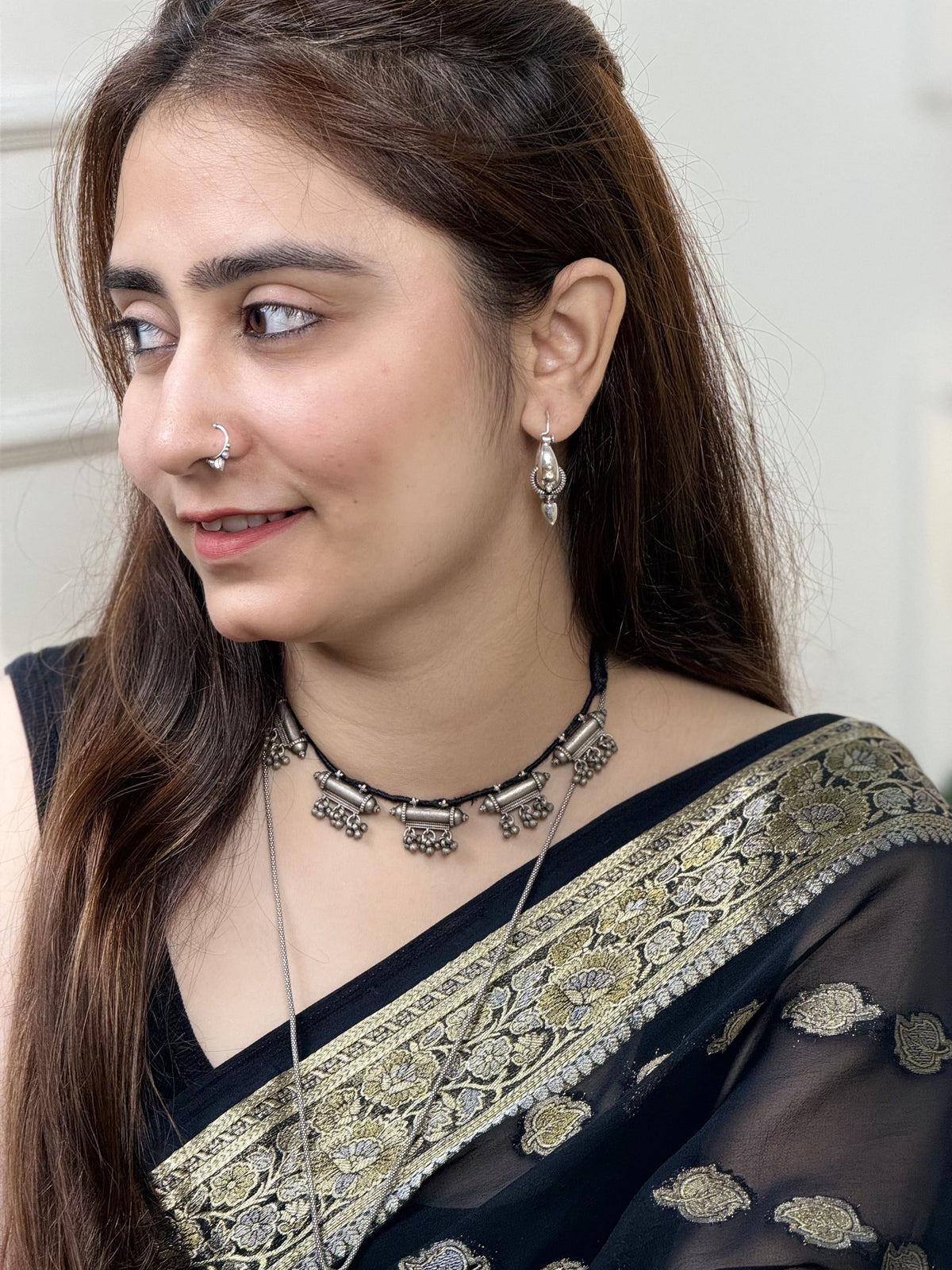 Vintage silver necklace with five taweez pendants on black dori — each with geometric embossing and three sets of three ghungroo clusters. Protective, ornate, heirloom. Shop Sadabahaar Jewelry.