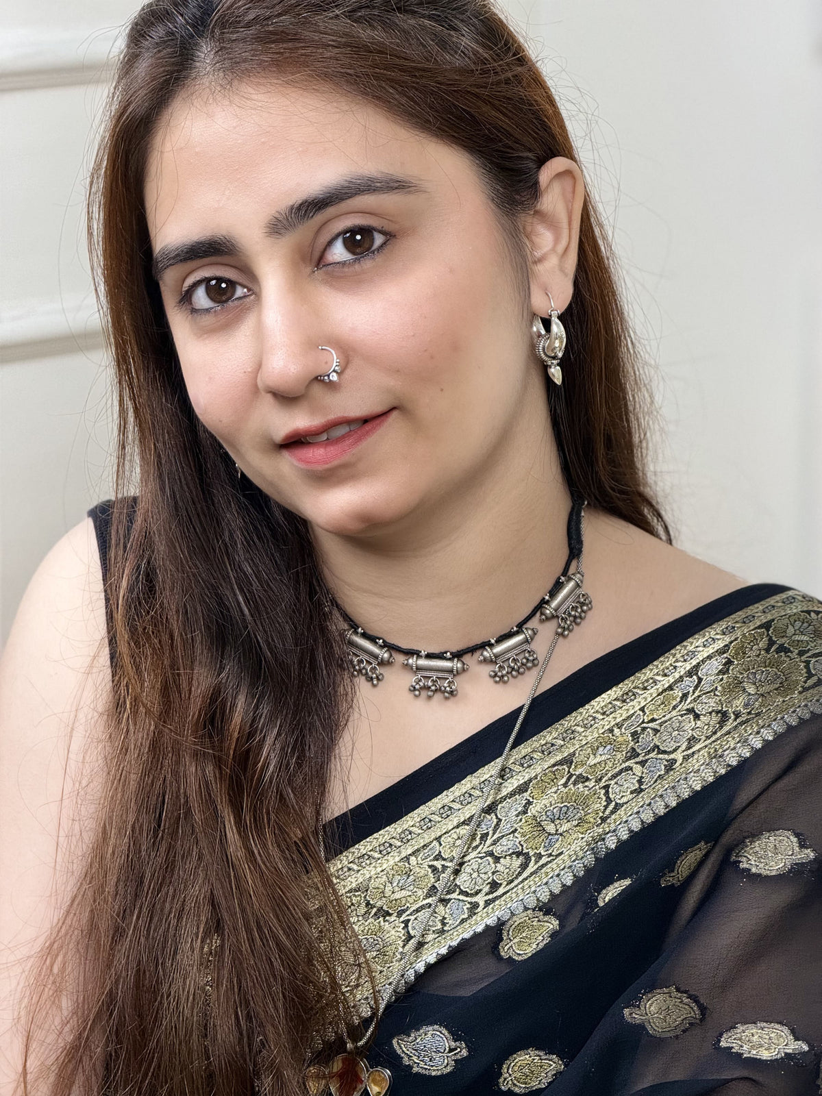 Vintage silver necklace with five taweez pendants on black dori — each with geometric embossing and three sets of three ghungroo clusters. Protective, ornate, heirloom. Shop Sadabahaar Jewelry. Front view