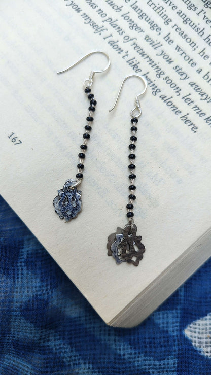 Pair of silver earrings with black beads on an open book | Sadabahaar Jewelry