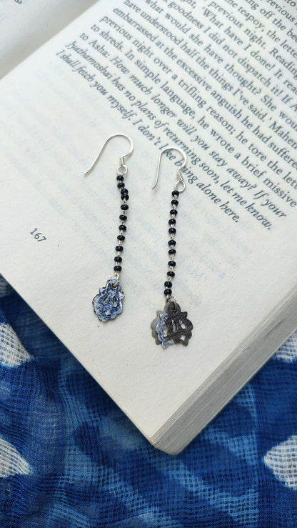 Pair of earrings on an open book with a blue fabric background