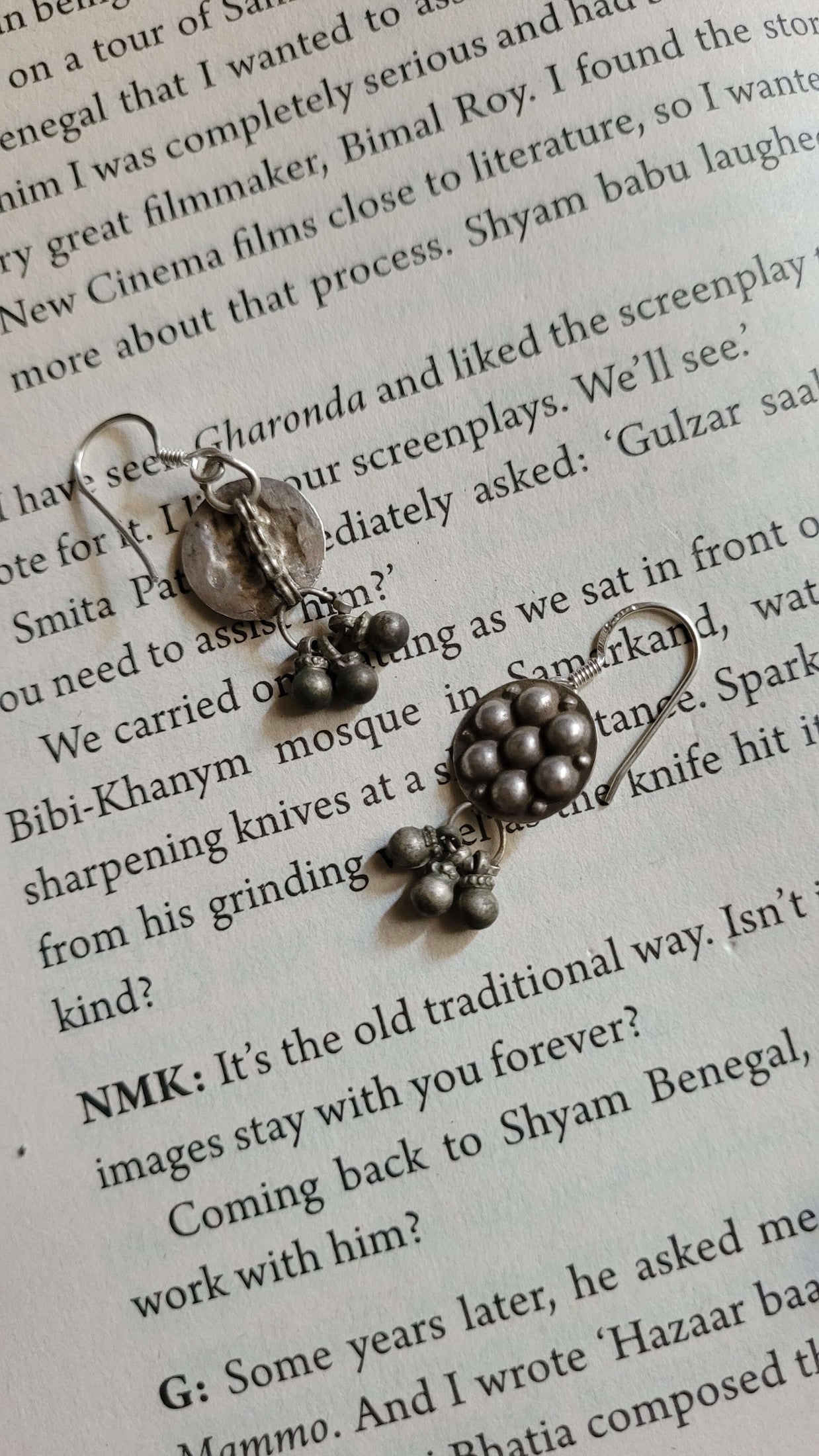 Silver earrings with bells on a book page