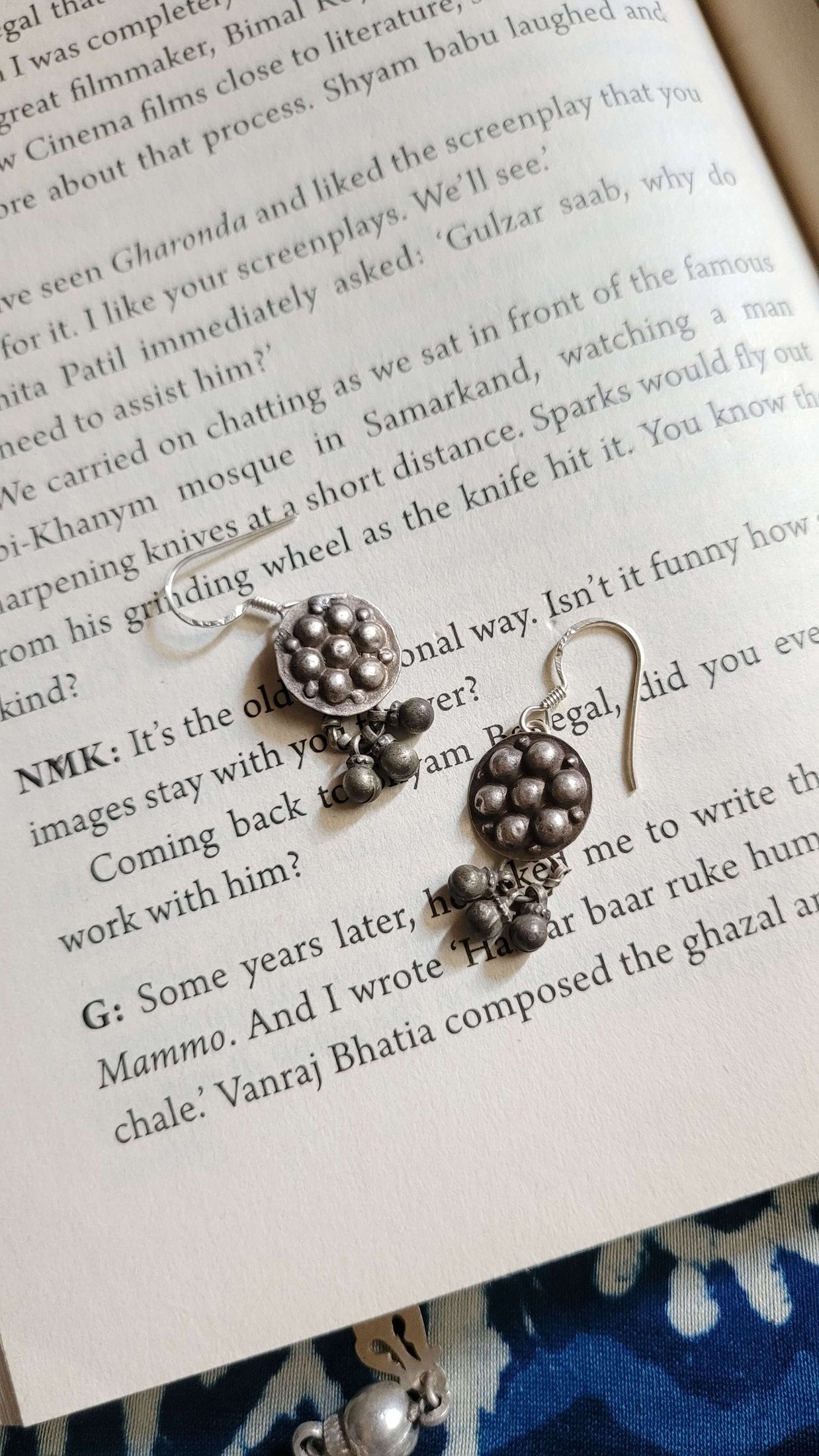 Silver earrings with ghungroos on a book page