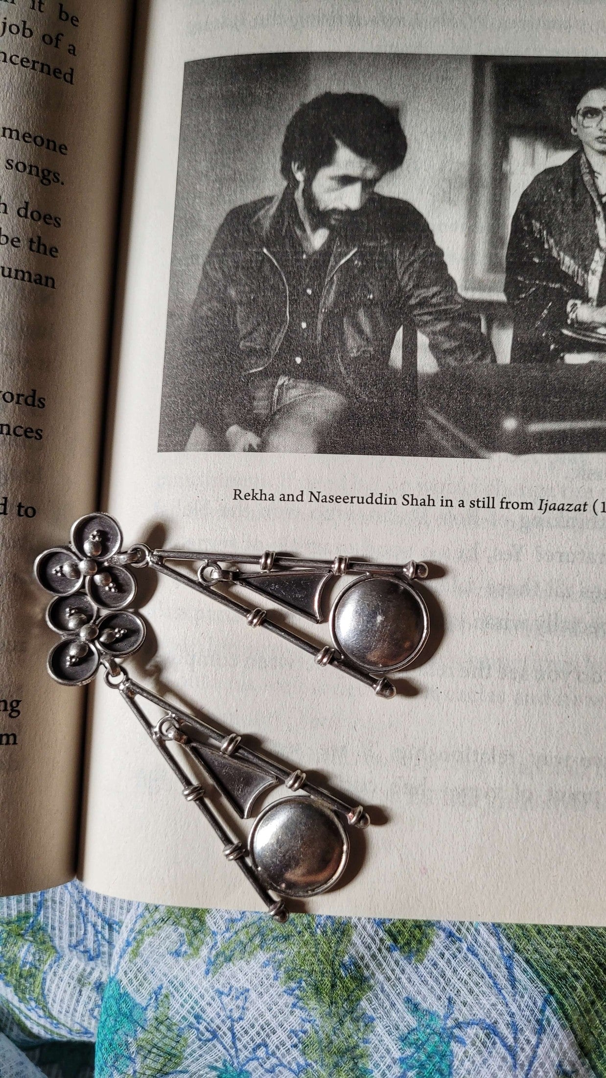 Silver jewelry on an open book with a vintage photo.