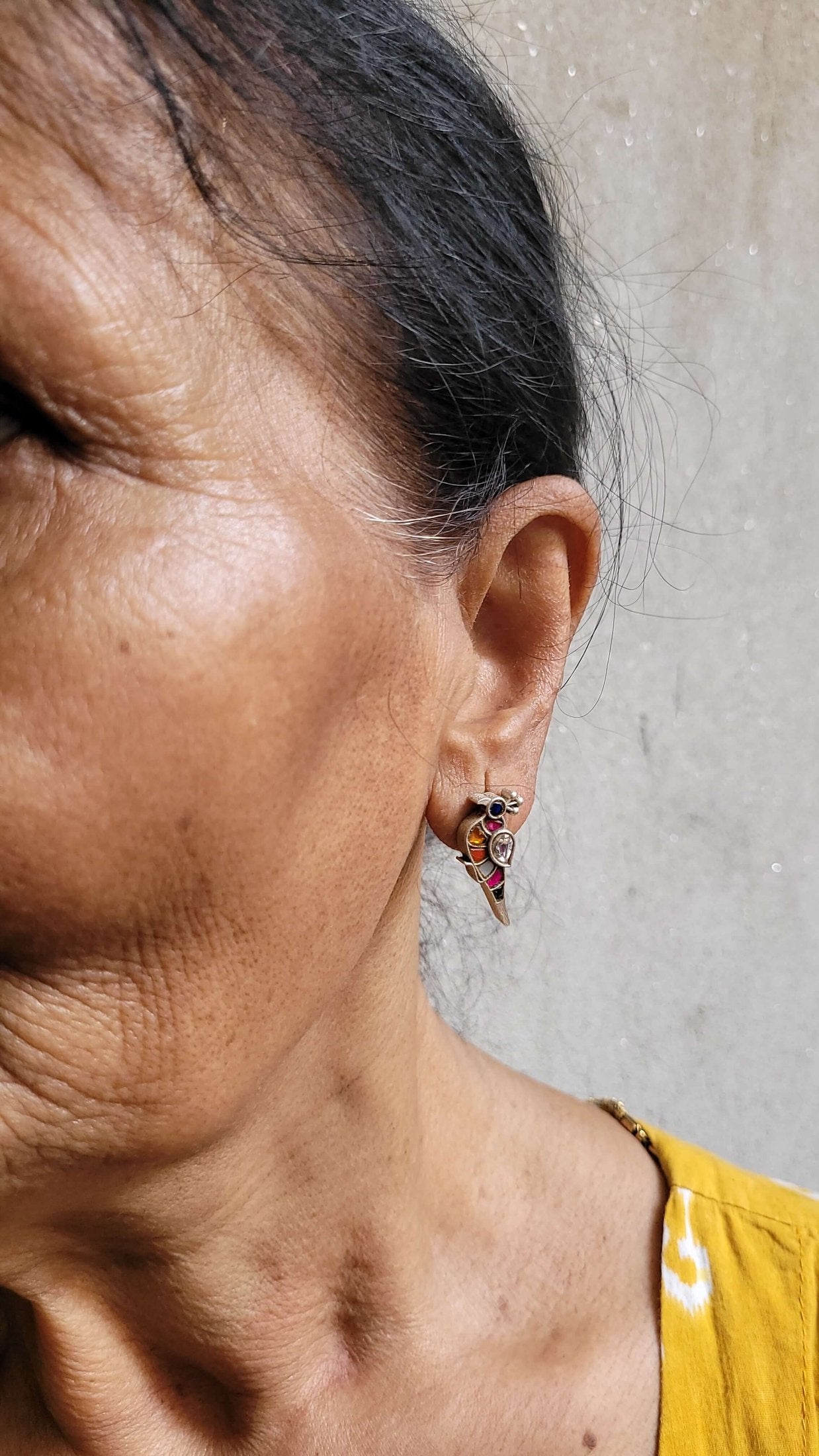 Close-up of a person wearing a colorful Bulbul Earrings against a plain background