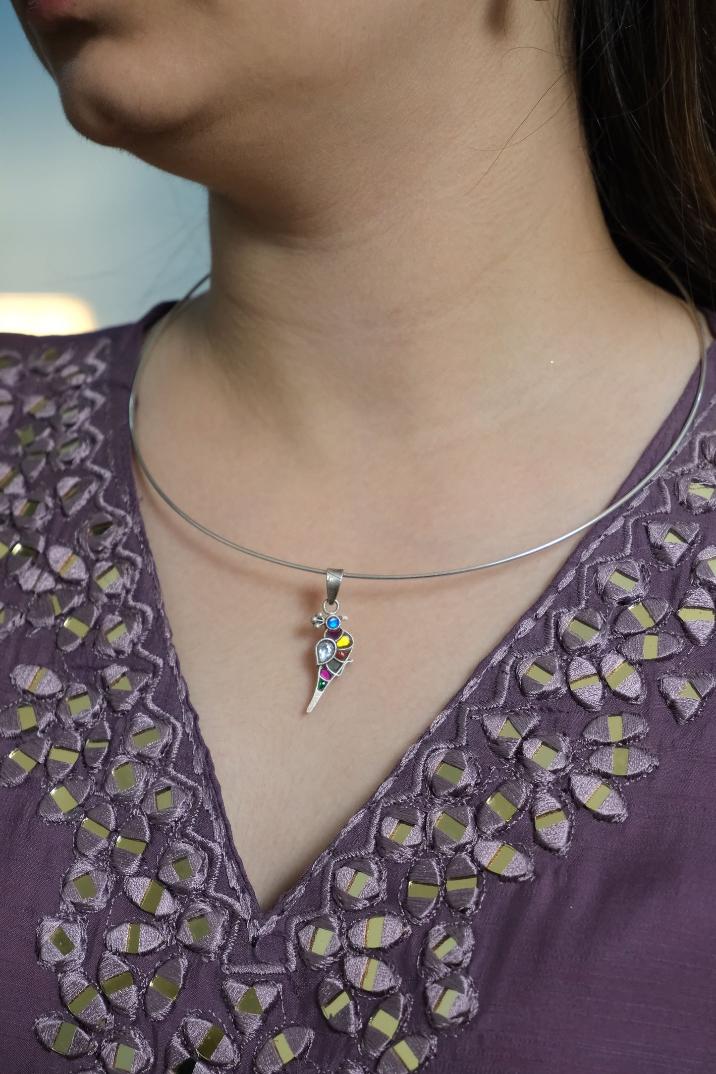 Close-up of a person wearing a colorful gemstone pendant.