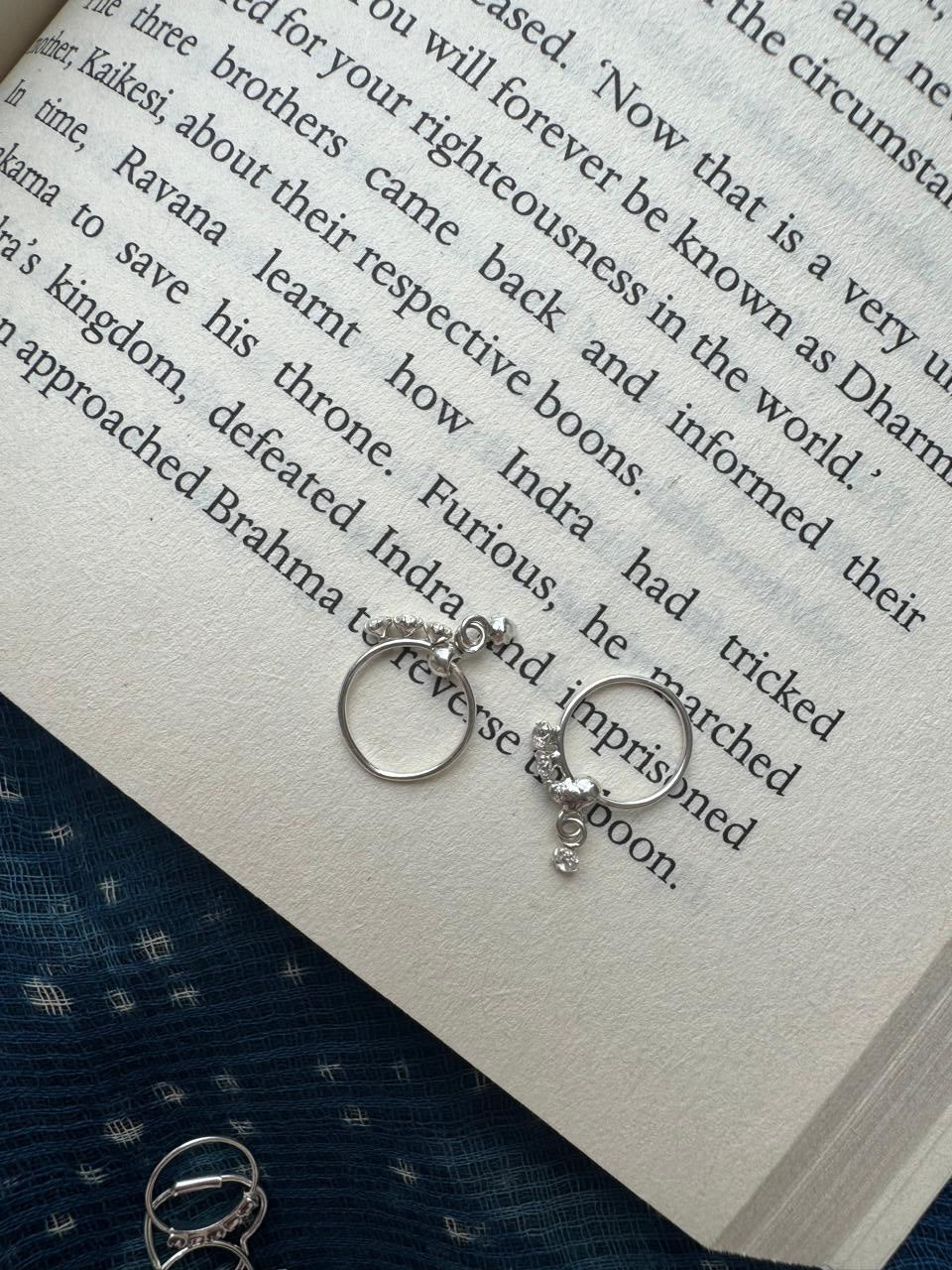 Silver hoops with round danglers on an open book