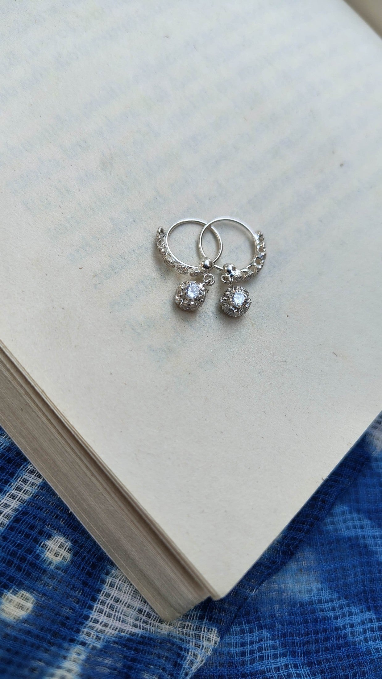 Silver hoop earrings with small round charms on a book | Sadabahaar Jewelry
