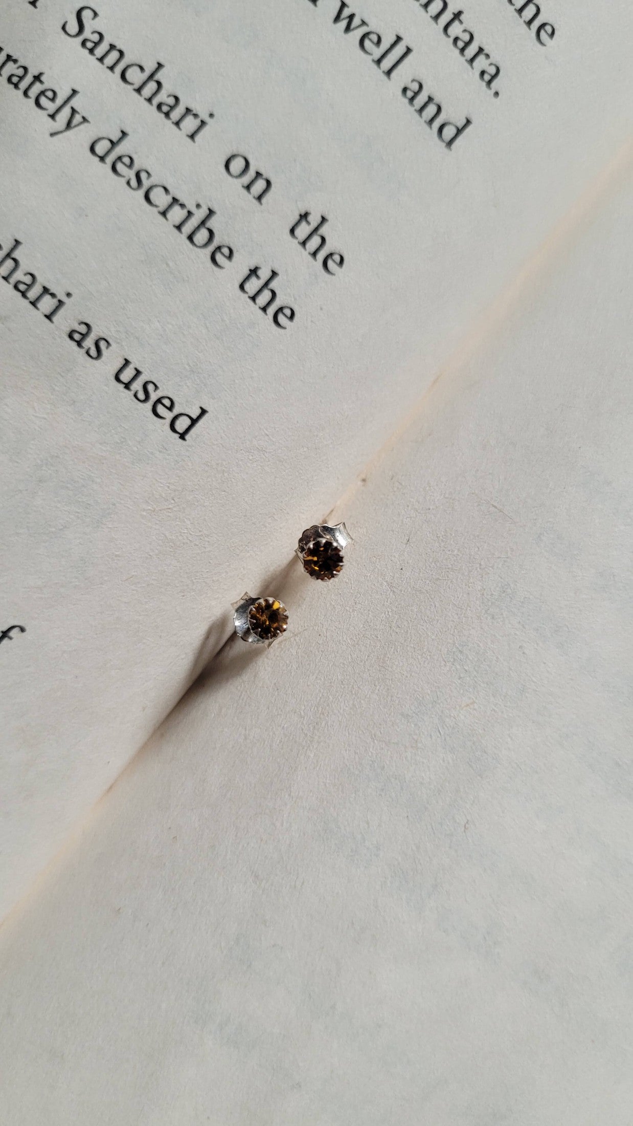 Two small earrings on a piece of paper with text