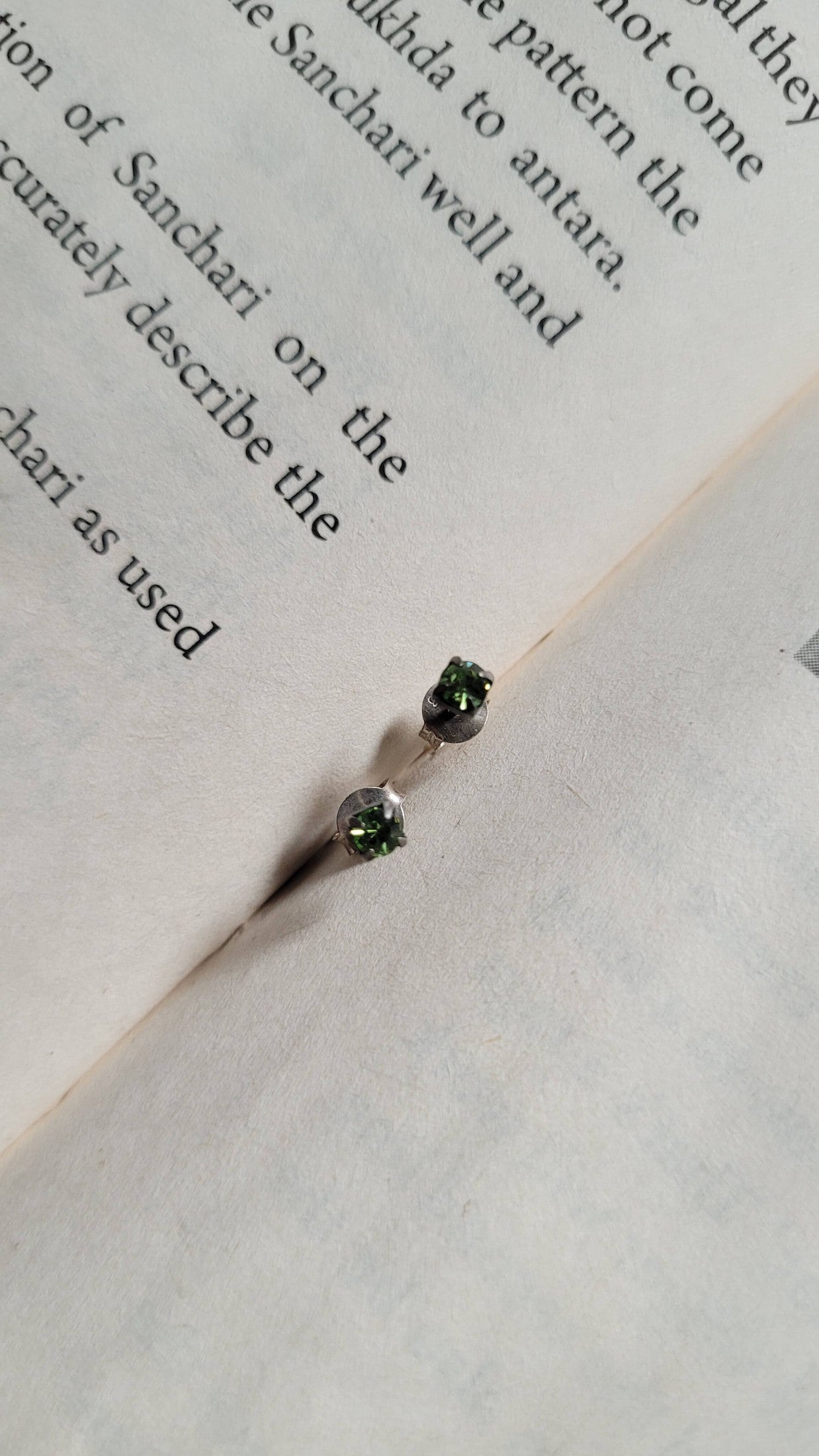 Jewelry with green gemstones on an open book
