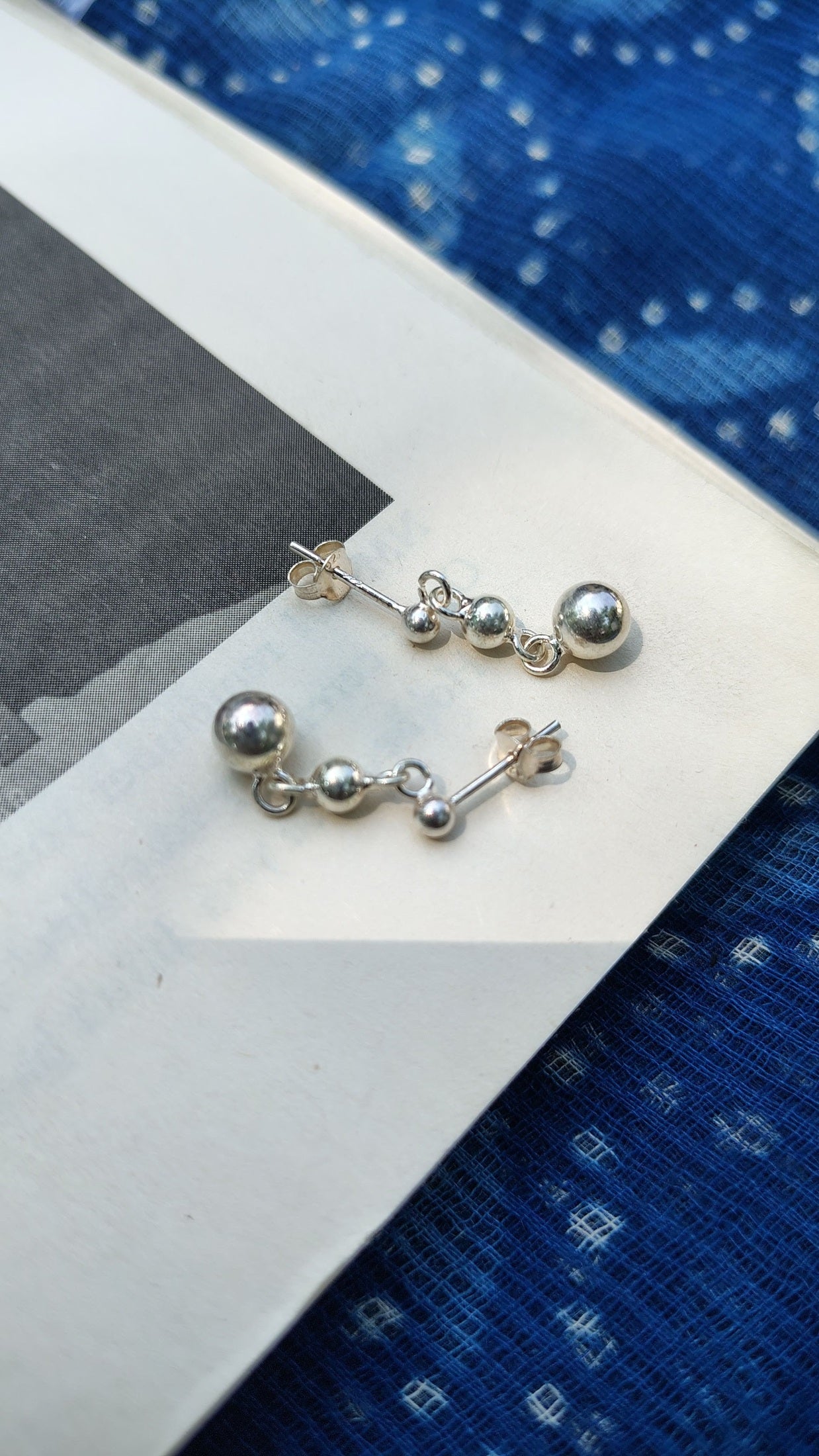 Silver earrings on a white card with a blue patterned background