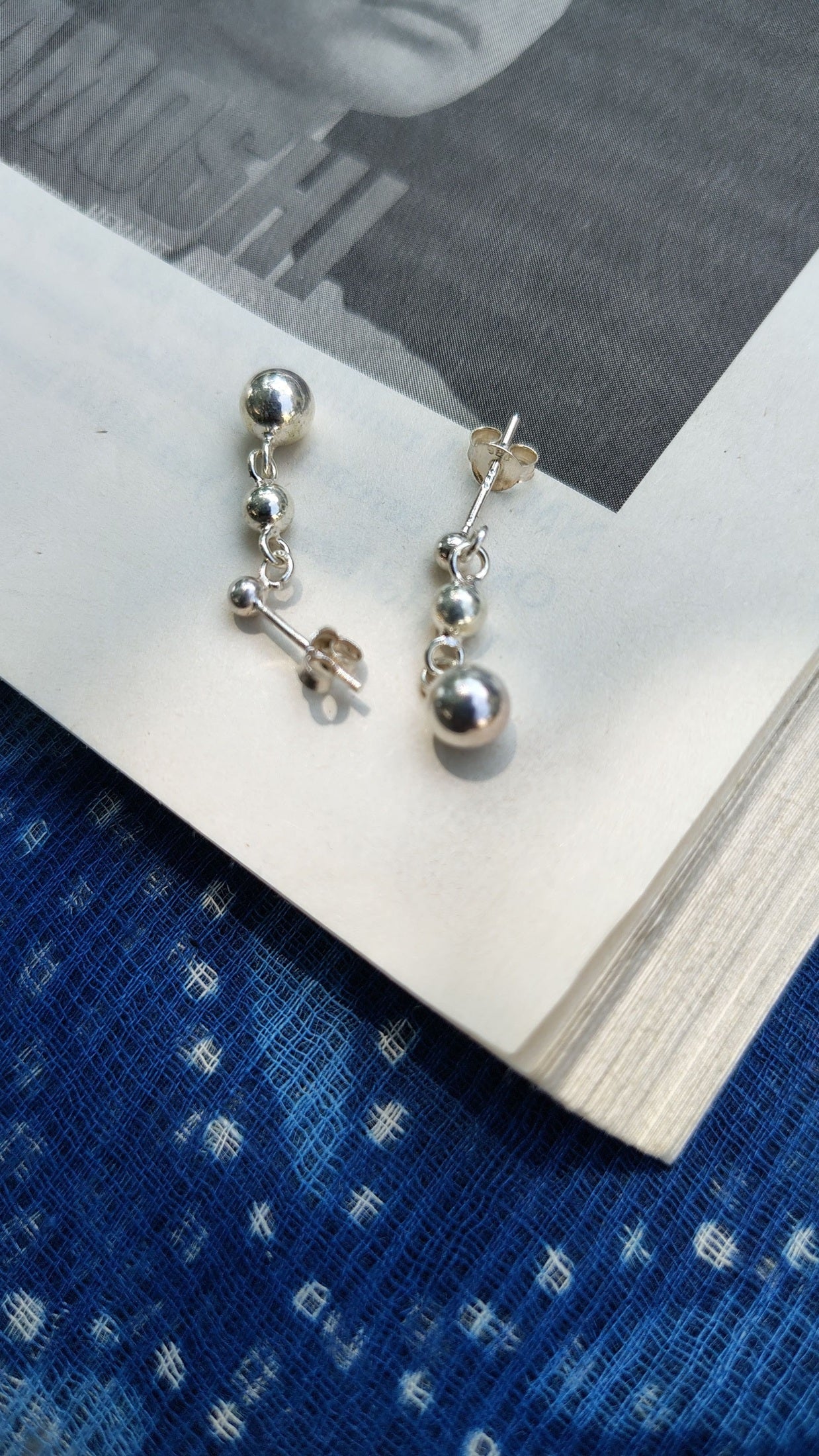 Silver earrings on a book with a blue fabric background
