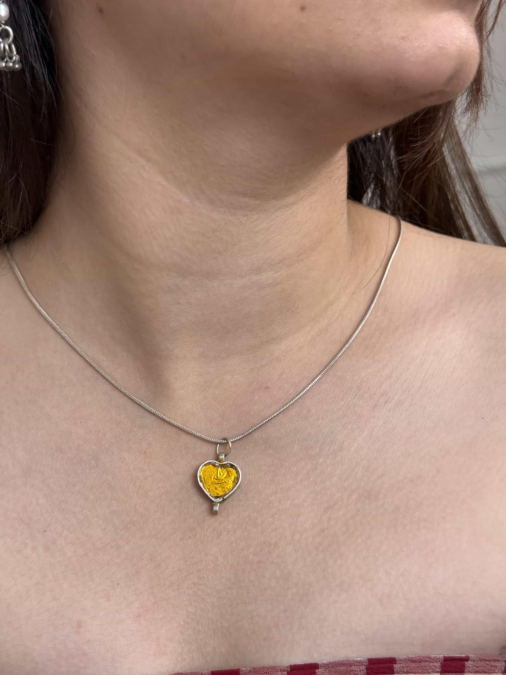 Necklace with a heart-shaped yellow pendant worn by a person