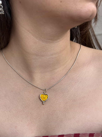 Necklace with a heart-shaped yellow pendant worn by a person