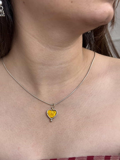 Necklace with a heart-shaped yellow pendant worn by a person