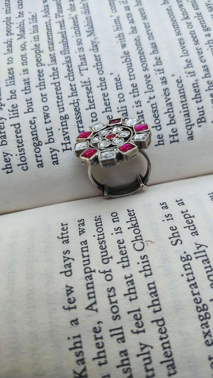Silver ring with pink and white kundan stones on an open book