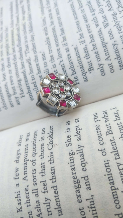 Silver ring with pink kundan on an open book
