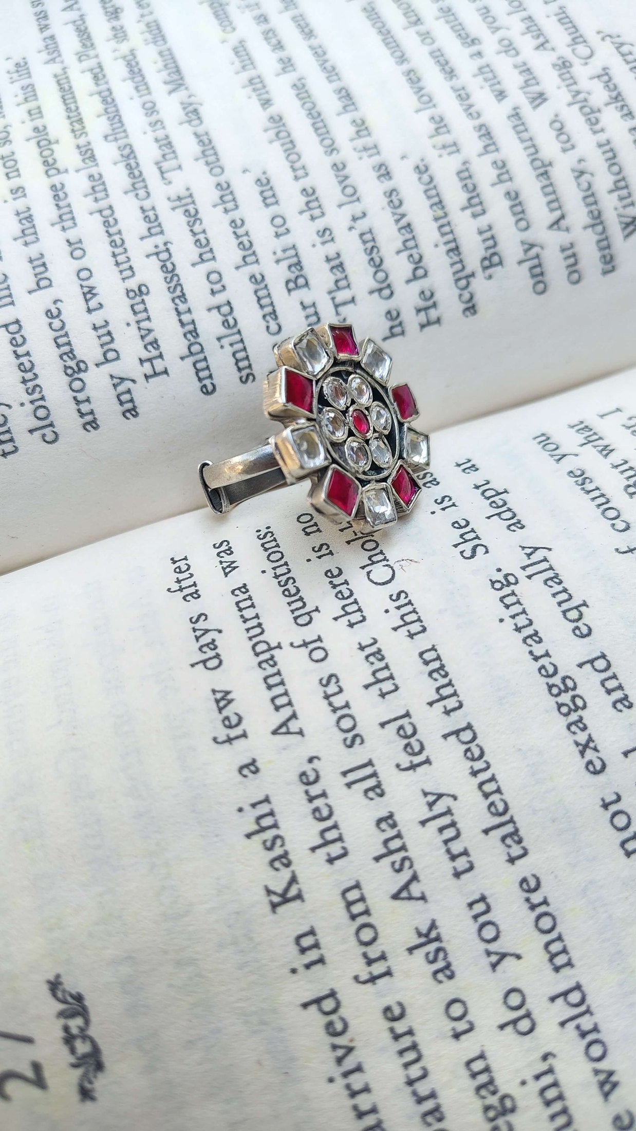 Silver ring with pink and white kundan on an open book