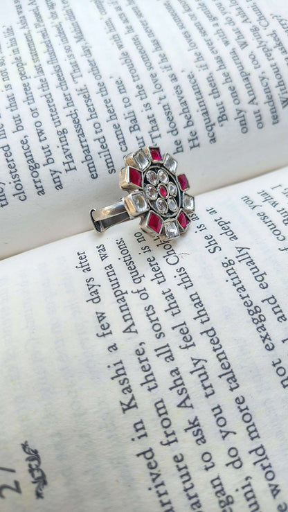 Silver ring with pink and white kundan on an open book