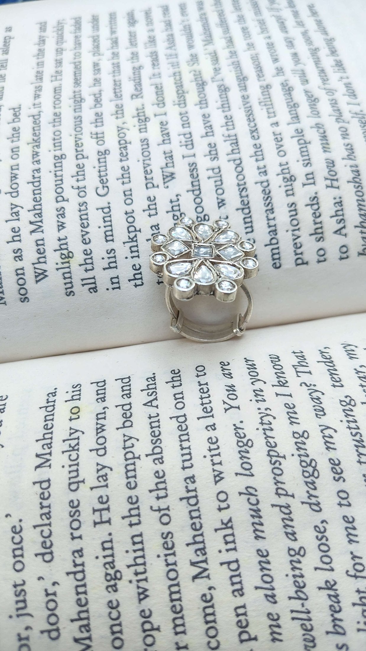 Silver ring with white kundan stones on an open book