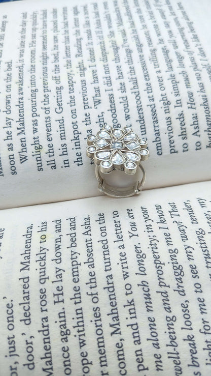 Silver ring with white kundan stones on an open book