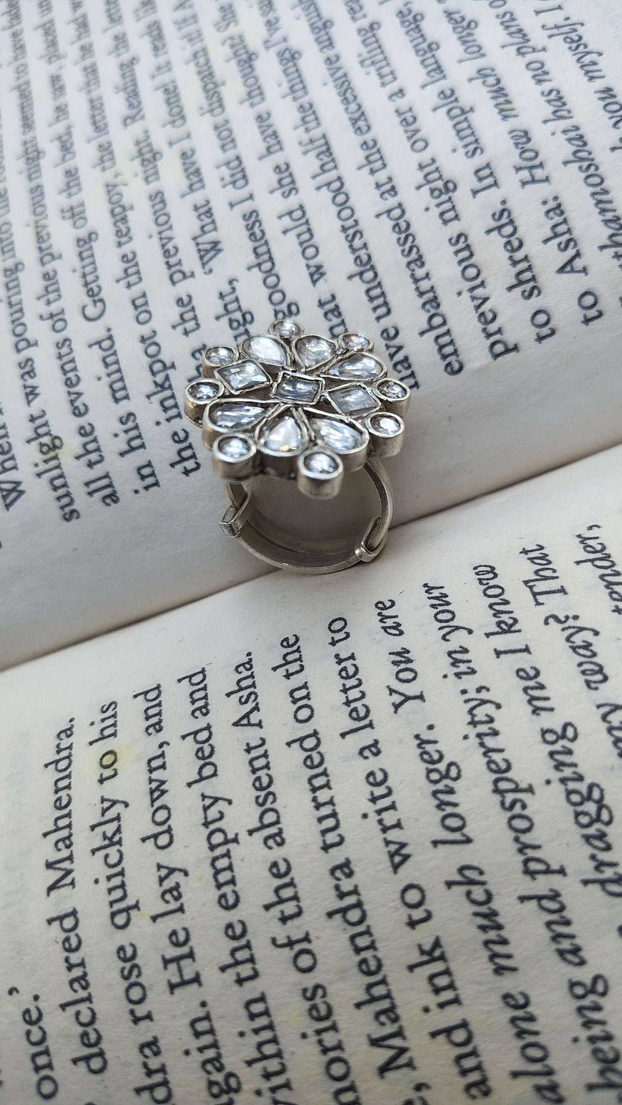 Silver ring with white kundan stones on an open book