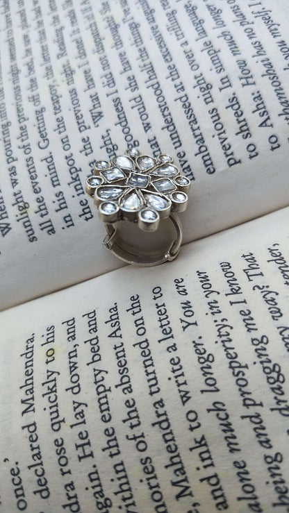 Silver ring with white kundan stones on an open book