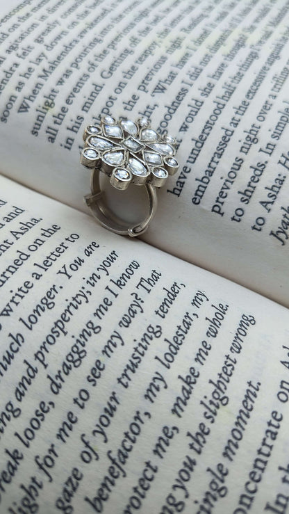 Silver ring with white kundan stones on an open book