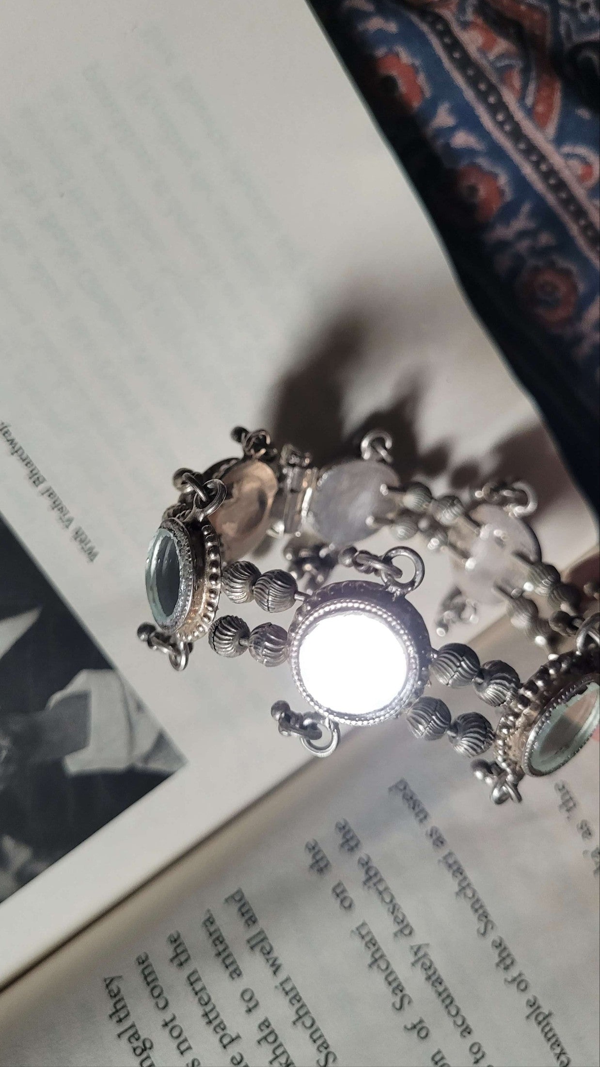 Silver glass bracelet with circular charms on an open book
