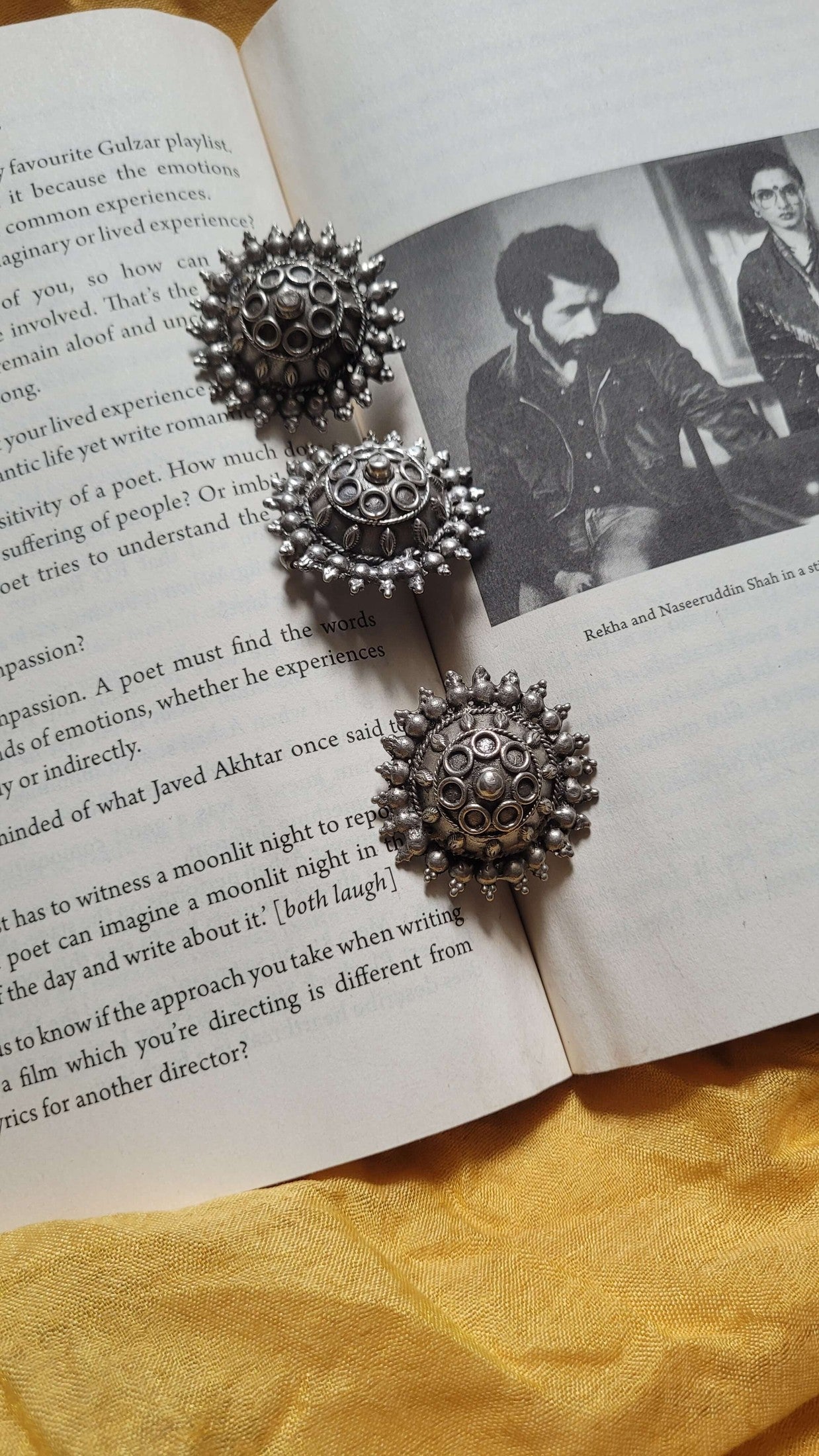 Gayatri Pendant set on an open book with a black and white photo of two people.