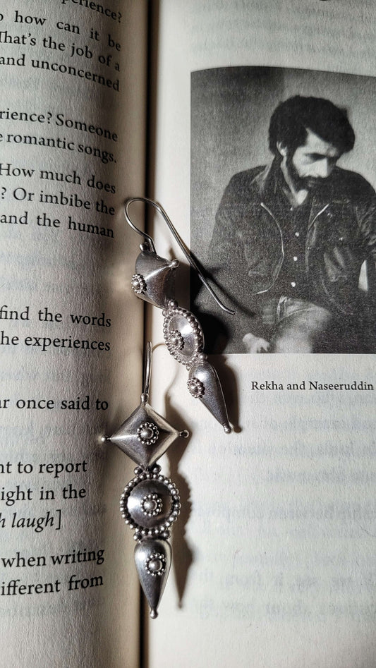 Silver earrings on an open book with a black and white photo of a man.