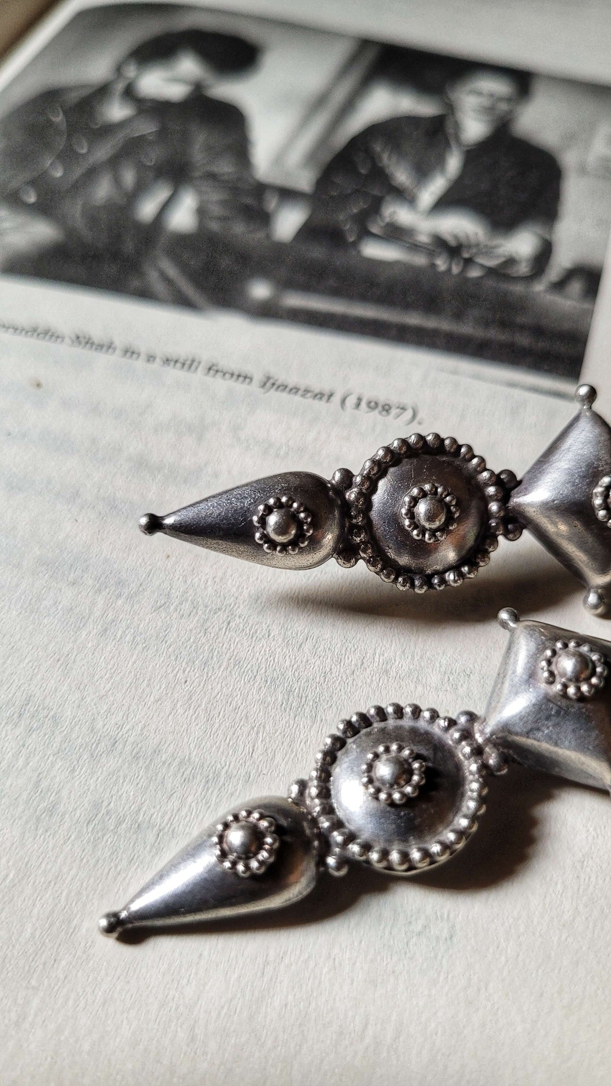 Silver earrings with intricate designs on a textured surface