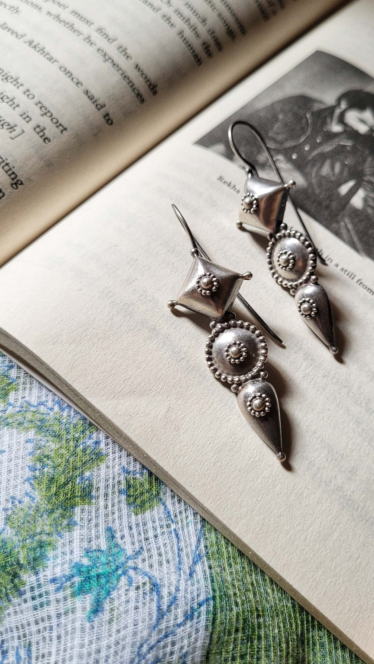 Silver earrings on an open book with a floral pattern