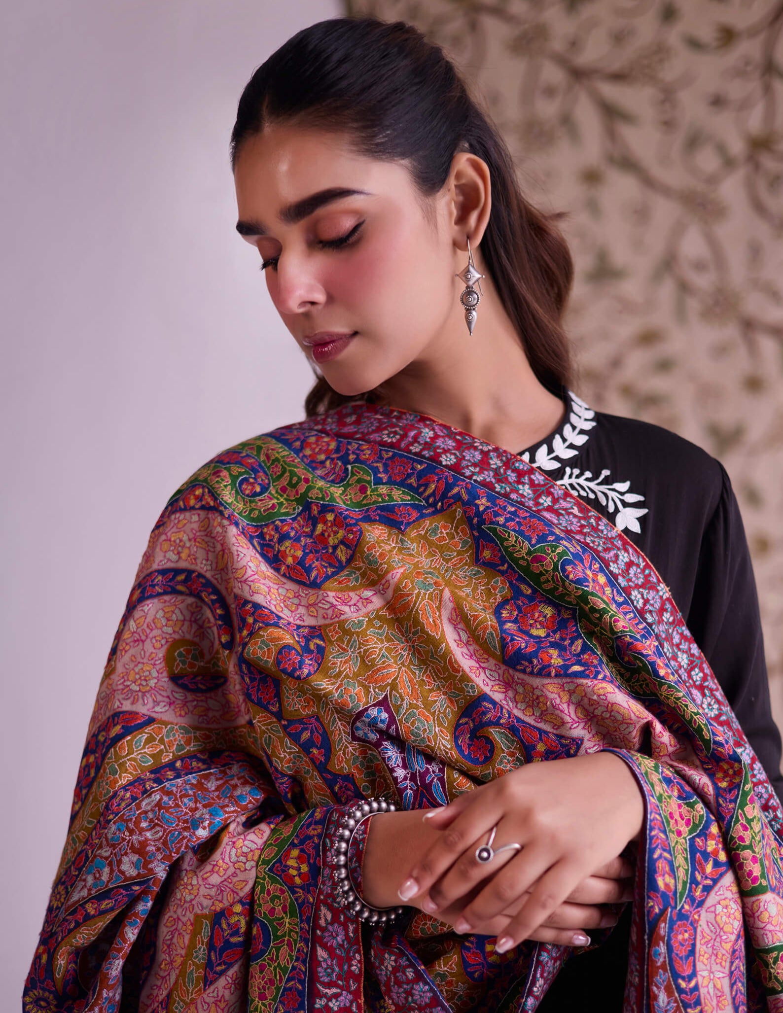 Woman wearing a colorful patterned shawl with a neutral background