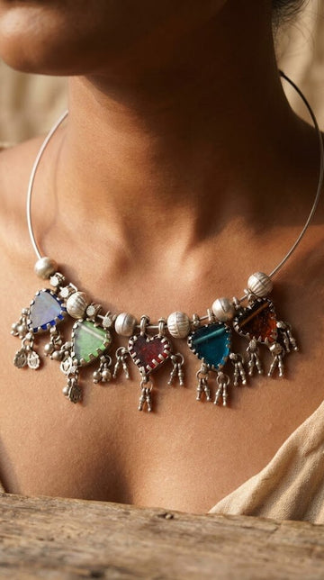 Necklace with colorful beads and charms worn by a person, with a blurred background.