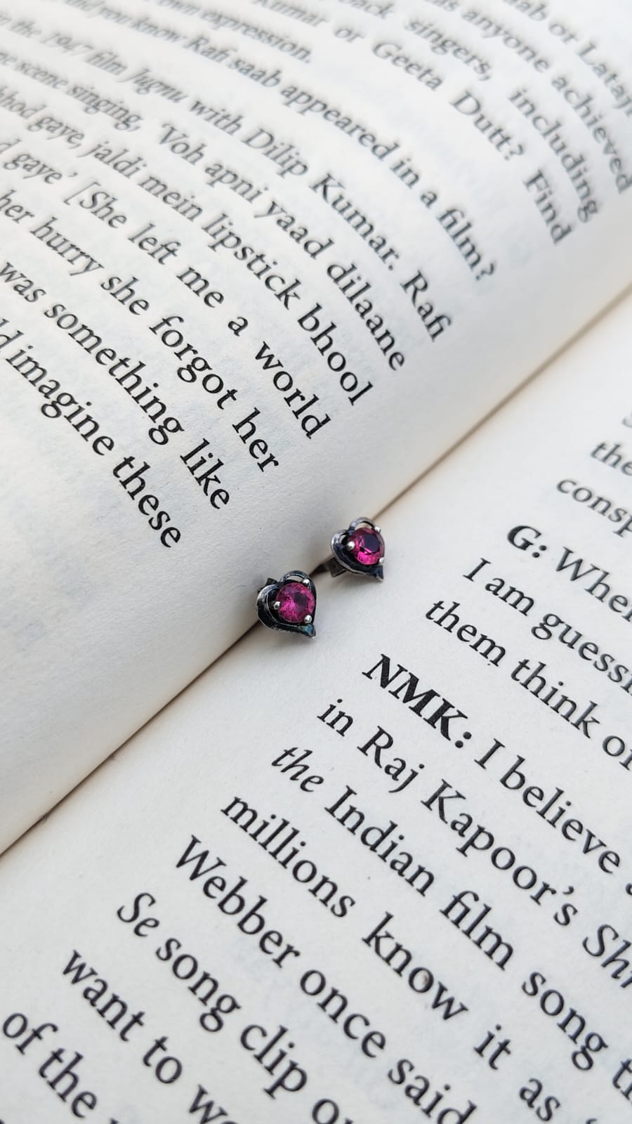 Pair of earrings with pink gemstones on an open book