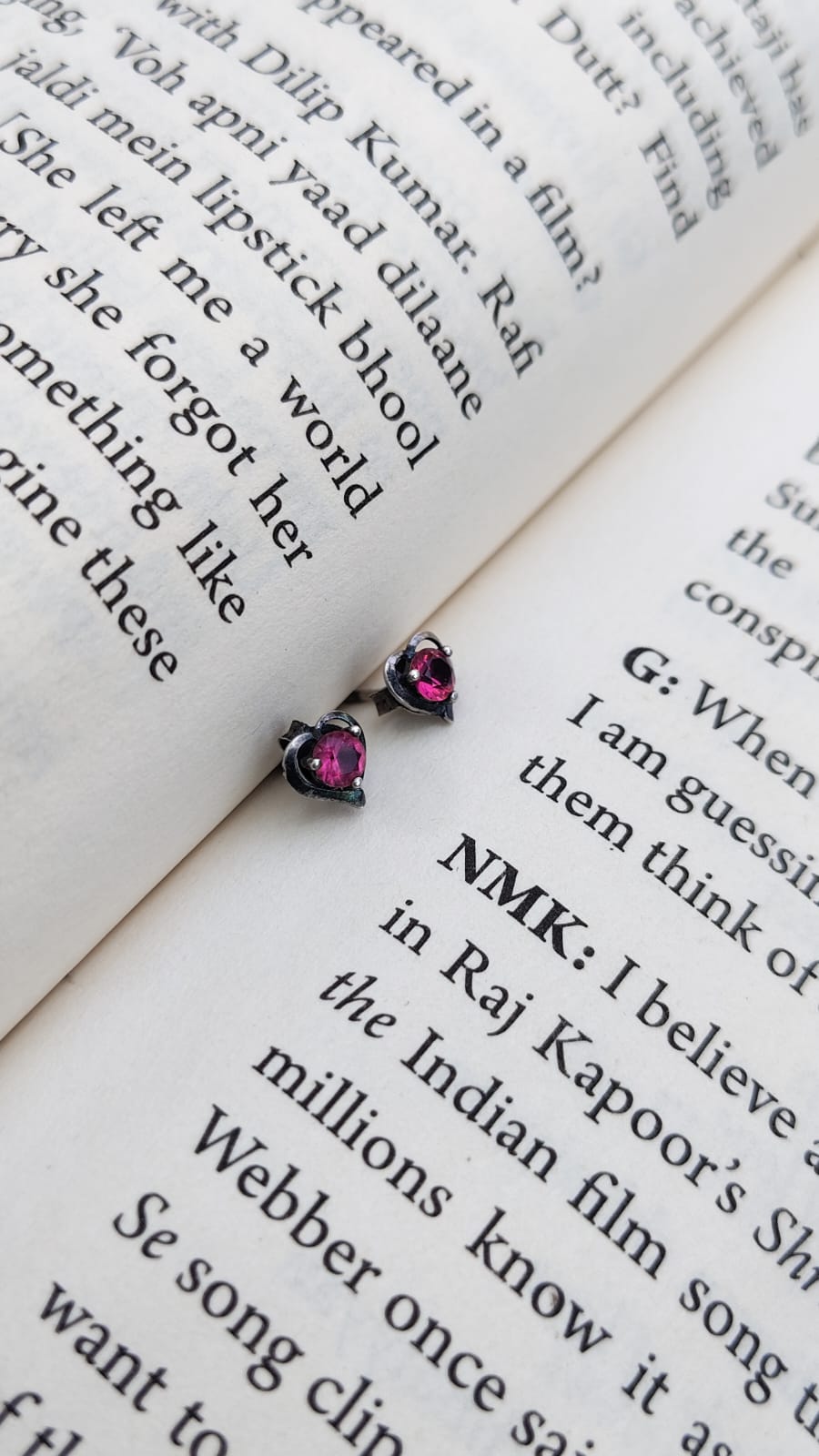 Pair of pink gemstone stud earrings on an open book