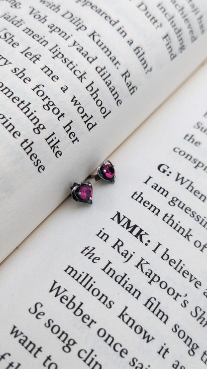 Pair of pink gemstone stud earrings on an open book
