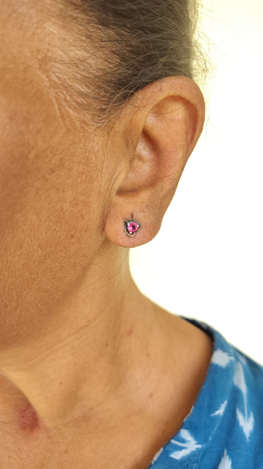 Close-up of an ear wearing a red stone 92.5 silver earring with a blurred background