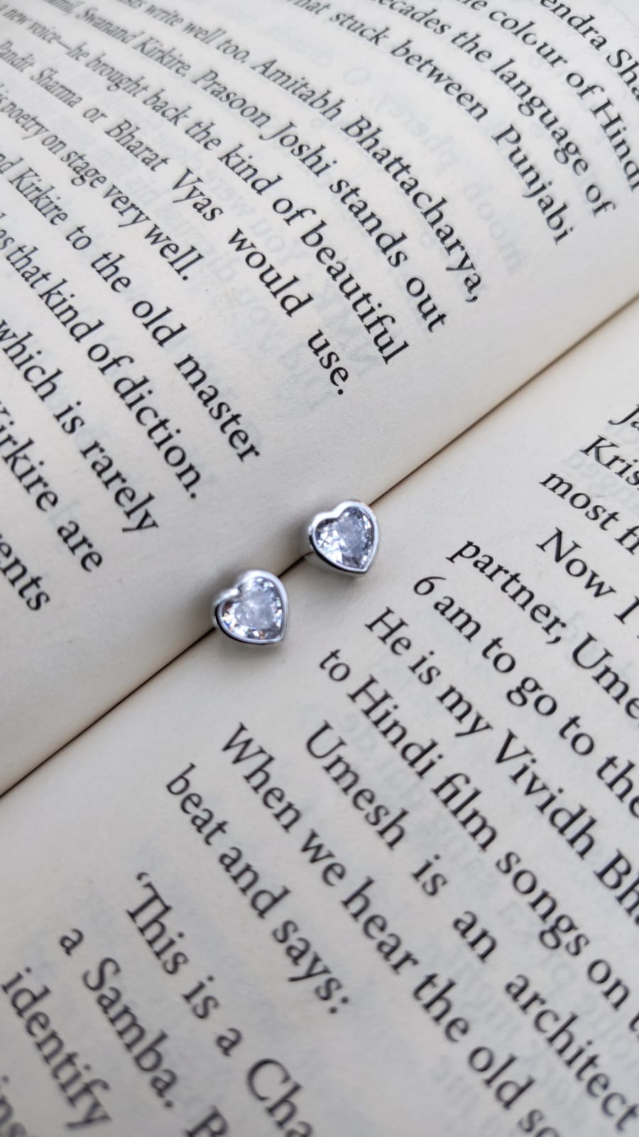 Heart-shaped and round stud earrings on a book page with text.