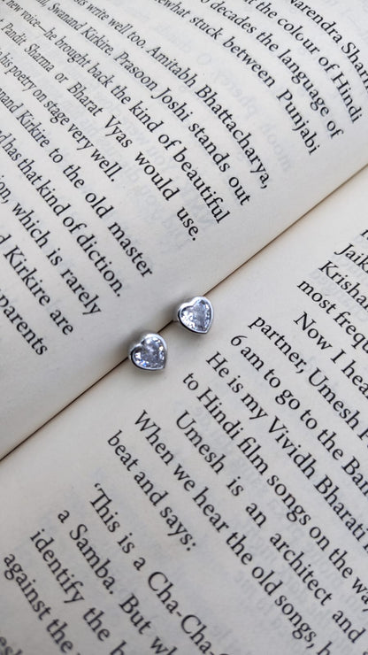 Two silver heart-shaped earrings on an open book