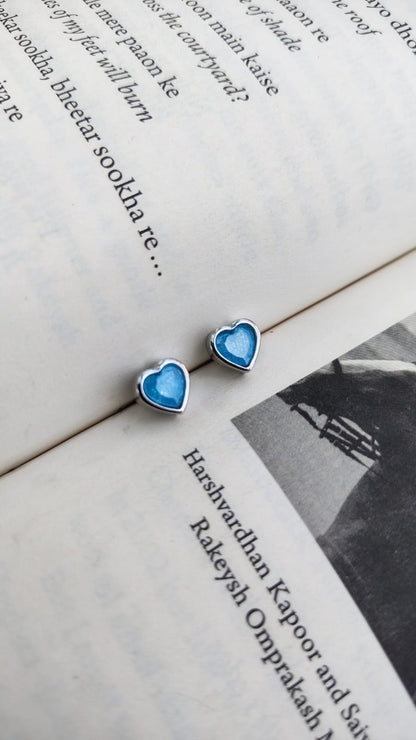 Blue heart-shaped earrings on an open book with text and a black and white photo.